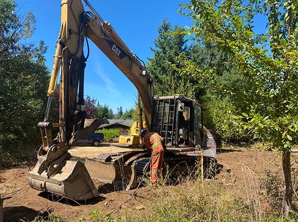 Heavy duty mechanic repairs excavator in empty lot