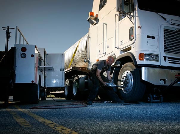 Mobile tire technician servicing vehicle tire with compressed air