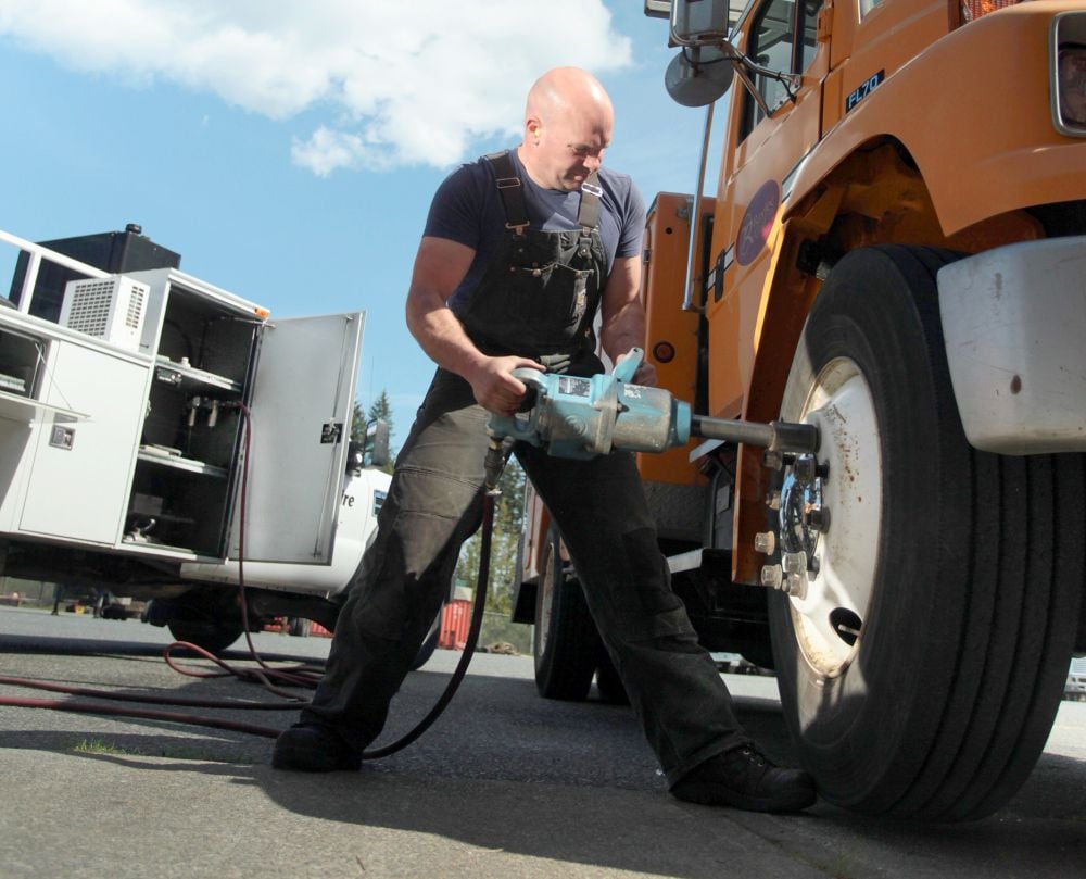 Operator using impact wrench to change vehicle tire