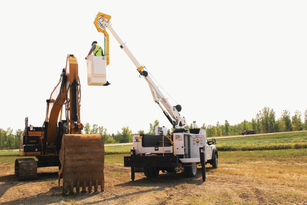Man working on excavator from a crane bucket, powered by a VMAC hydraulic compressor