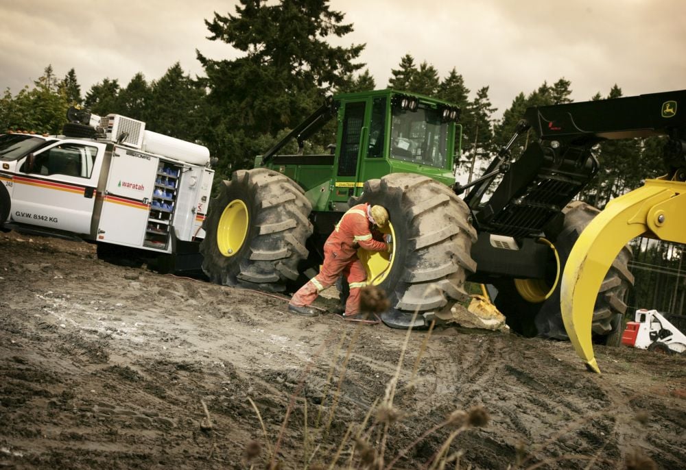 Mechanic services tractor tire using service truck with hydraulic compressor