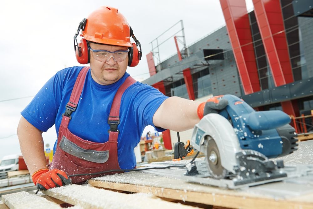 Construction worker cuts wood with circular saw