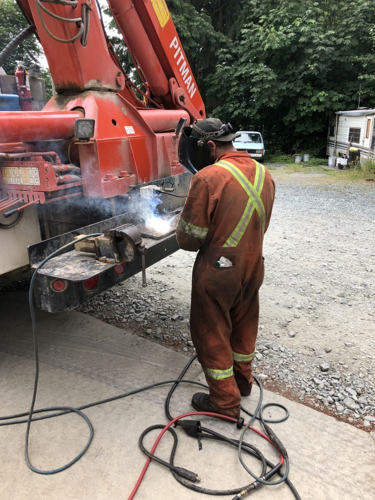 Field mechanic welds on the back of his service truck