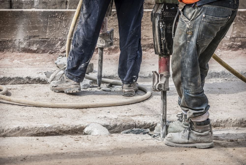 Two workers jackhammering concrete