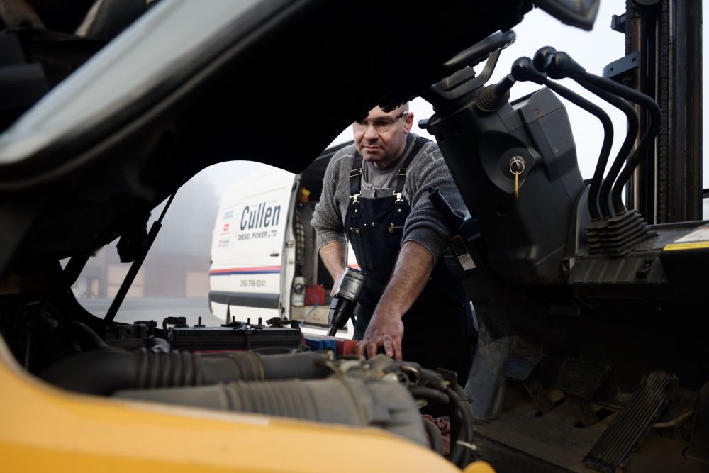 Mechanic repairs forklift with impact wrench powered by UNDERHOOD40