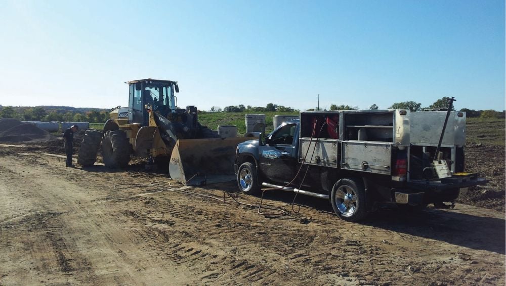 A work truck with UNDERHOOD70 servicing John Deere tractor tires